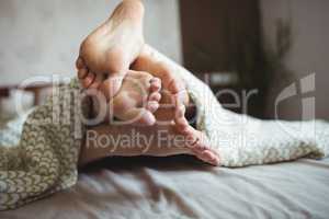 Couple showing their feet while lying on a bed