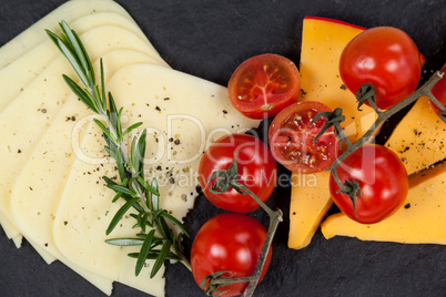 Cheese with tomatoes and rosemary on slate board