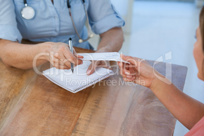 Doctor giving a prescription to her patient in medical office