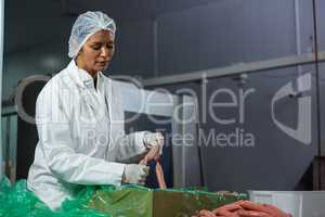 Female butcher processing sausages