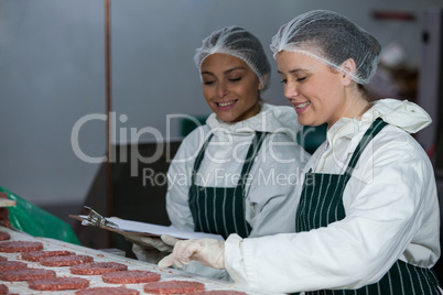 Female butchers maintaining records on clipboard