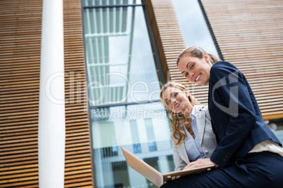 Businesswomen sitting with laptop in office premises