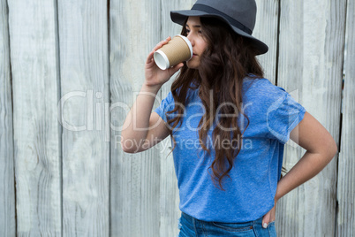 Woman in blue top drinking coffee from disposable cup