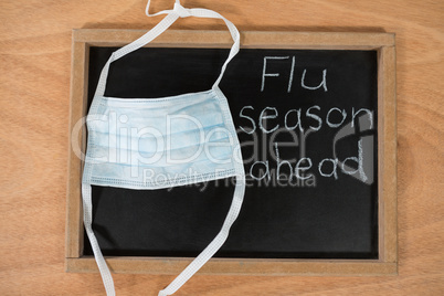 Flue season ahead written on chalk board with medical mask