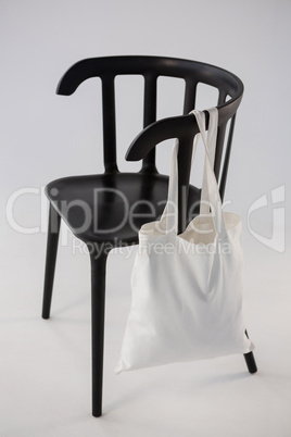 White bag hanging on a black chair