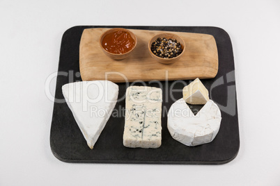 Sliced cheese, bowls of jam and spices on chopping board