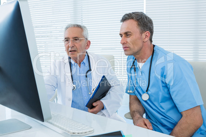 Surgeon and doctor discussing over personal computer