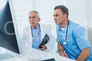 Surgeon and doctor discussing over personal computer