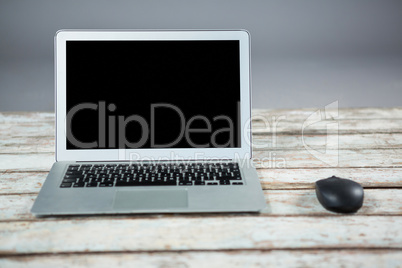 Laptop and mouse on wooden table