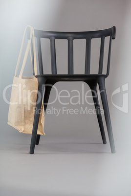 Beige colored shopping bag hanging on black chair