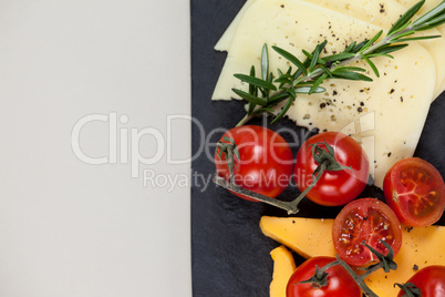 Cheese with tomatoes and rosemary on slate board