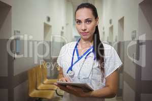 Portrait of female nurse using digital tablet in corridor