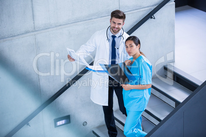 Doctor and nurse holding medical report and climbing down stairs