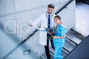 Doctor and nurse holding medical report and climbing down stairs
