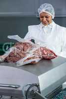 Female butcher packing raw meat