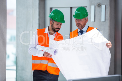 Architects discussing with blueprint