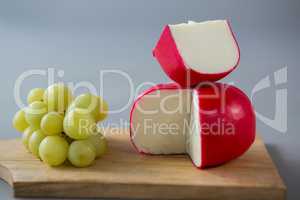 Gouda cheese with grapes on chopping board