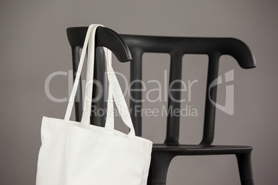 White shopping bag hanging on black chair