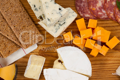 Variety of cheese with biscuits on chopping board