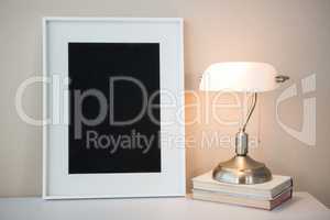 Picture frame with books and table lamp