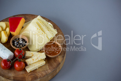 Variety of cheese with cherry tomato, sauce and spices on wooden board