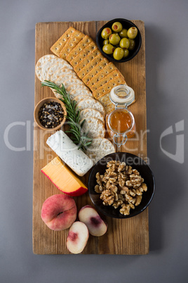 Variety of cheese with olives, peach, honey, rosemary, walnuts and crackers