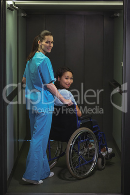 Portrait of female nurse assisting patient on wheelchair in corridor