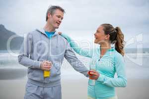 Couple drinking water after exercise on beach