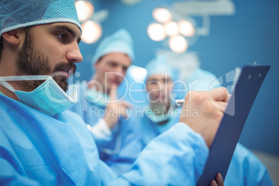 Team of surgeons having discussion over clipboard