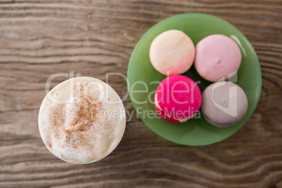 Disposable coffee cup and macaroons on wooden table