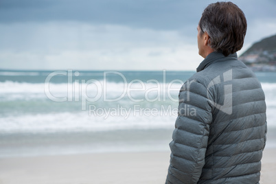 Thoughtful man standing on beach