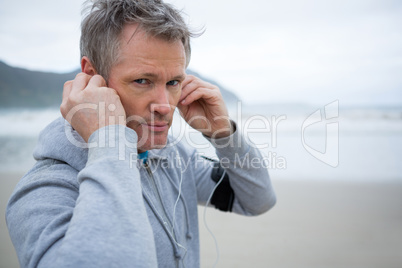 Portrait of man listening music on headphones at beach