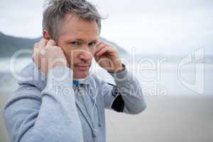 Portrait of man listening music on headphones at beach