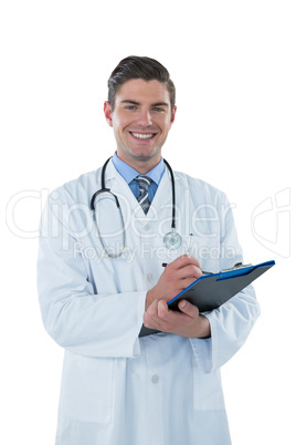 Smiling doctor writing with pen on clipboard