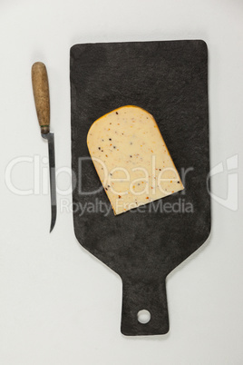 Slice of cheese and knife on chopping board