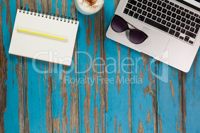 Laptop, sunglasses, coffee mug, notepad and pencil