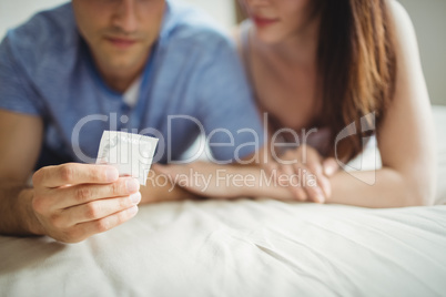 Close-up of couple with a condom on bed