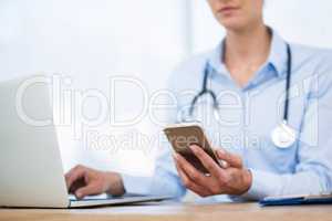 Doctor using laptop and mobile phone