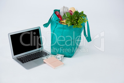 Grocery bag with banknotes and laptop