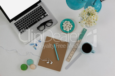 Laptop, spectacles, earphones, flowers, macaroons and office desk tops