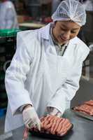 Female butcher packing raw sausages