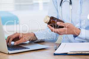 Doctor maintaining record of medicine in laptop
