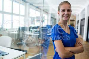 Female graphic designer standing with arms crossed in office