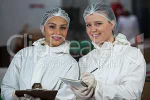 Female butchers holding clipboard and diary