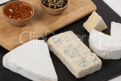 Sliced cheese, bowls of jam and spices on chopping board