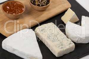 Sliced cheese, bowls of jam and spices on chopping board
