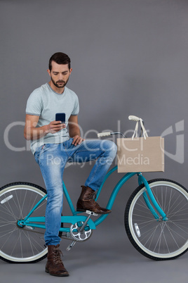 Man sitting on a bicycle and using mobile phone