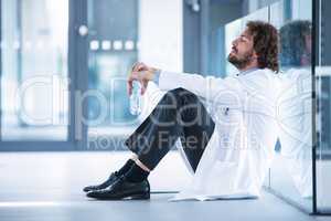 Worried doctor sitting on floor