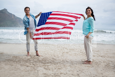 Portrait of couple holding american flag on beach