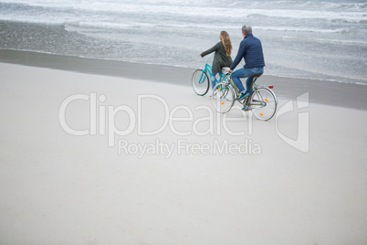 Couple riding bicycle on beach